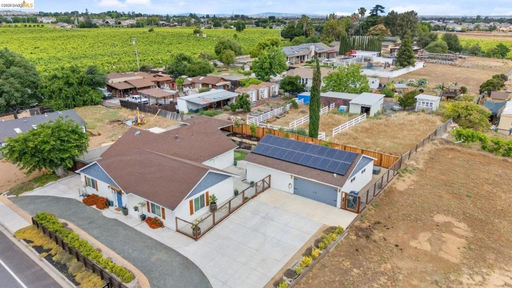 Property featuring a spacious main residence, a detached garage with solar panels, a paved driveway, and ample undeveloped land