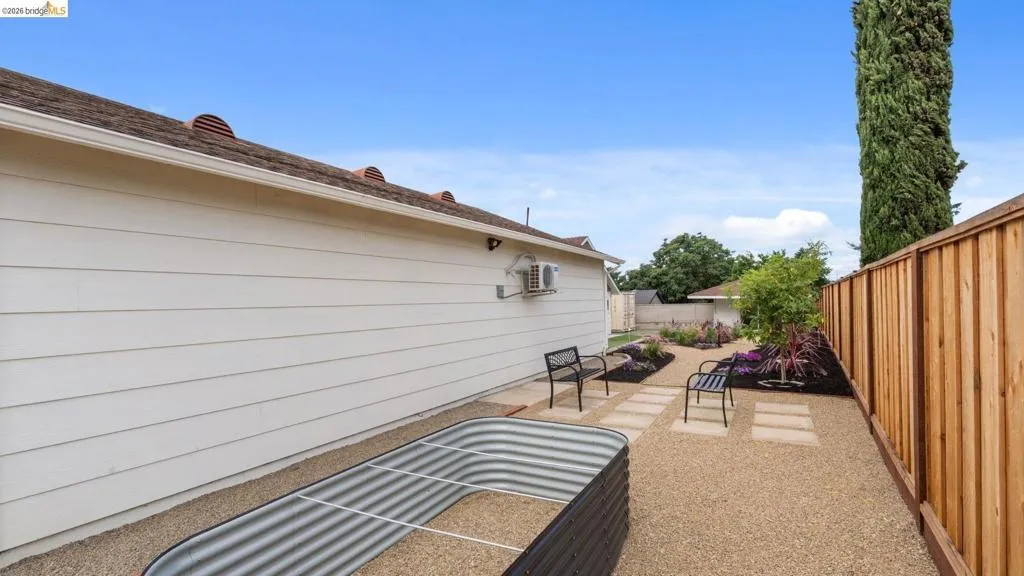 Expansive side yard featuring gravel landscaping, a raised garden bed, and a new privacy fence
