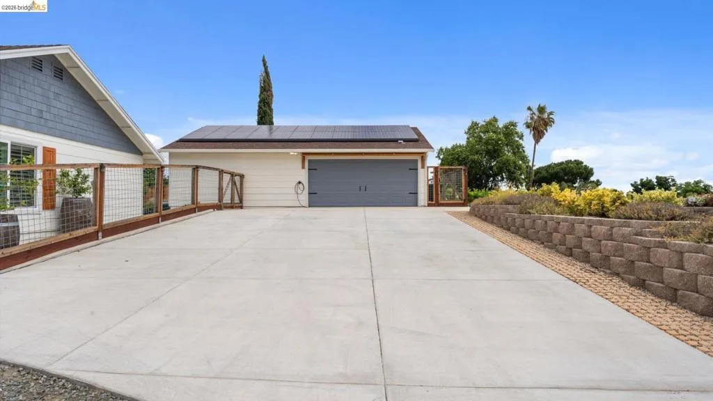 Expansive concrete driveway leading to a detached garage with solar panels