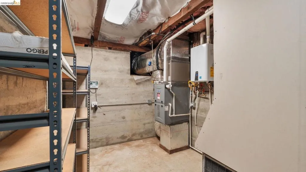 Utility area featuring concrete walls, exposed ceiling joists, and a skylight
