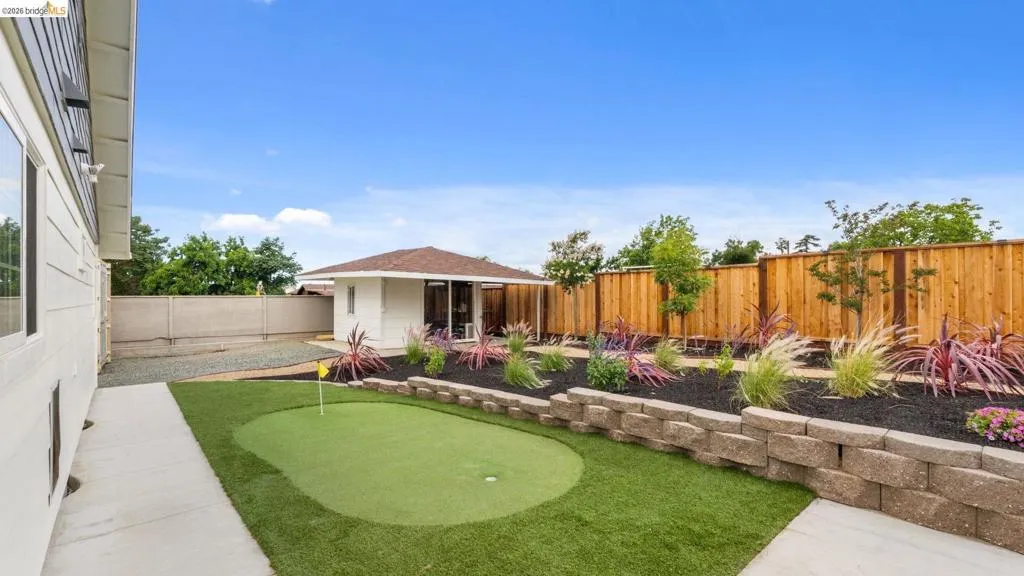 Putting green with artificial turf, bordered by a concrete walkway