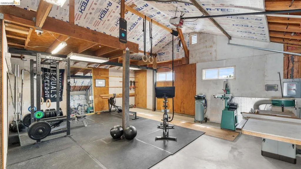 Spacious interior with exposed wooden beam ceiling, concrete walls, and large windows