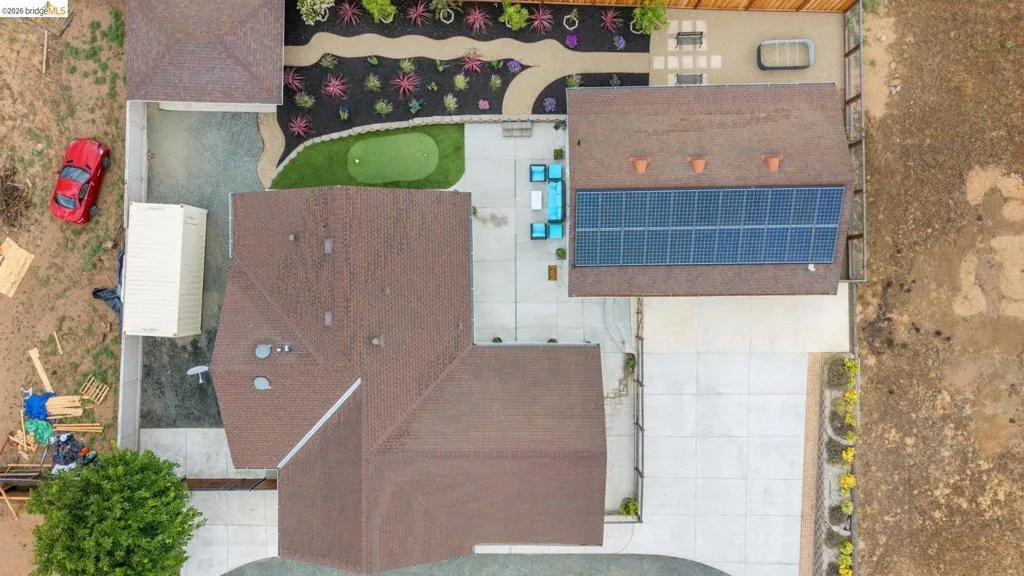 Expansive backyard featuring a putting green, paved patio areas, and varied landscaping