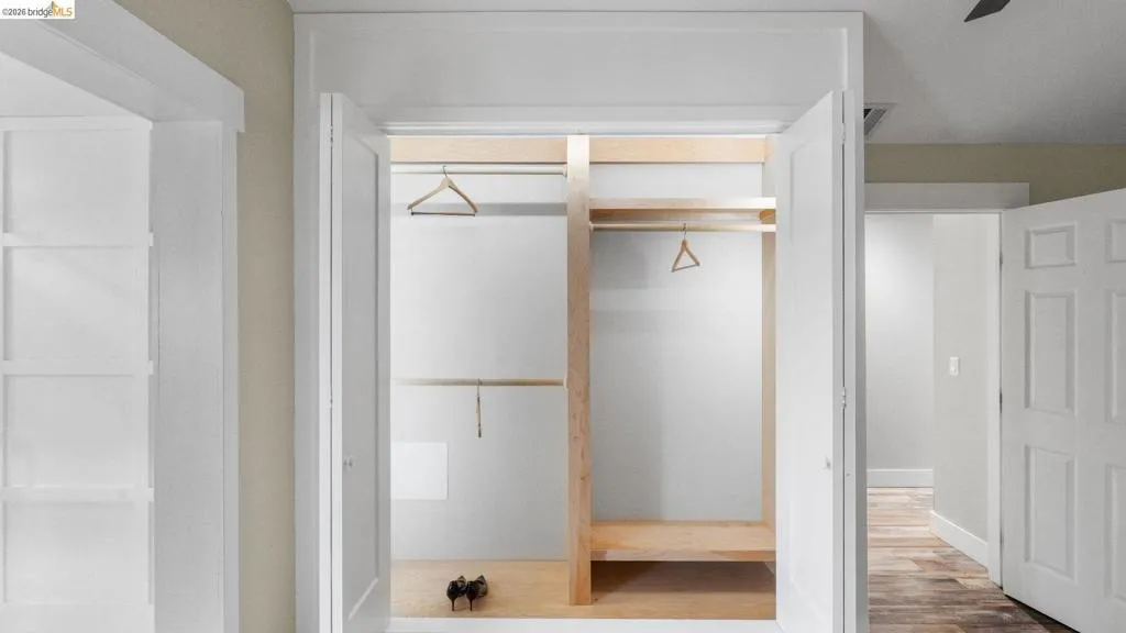 Bedroom featuring a built-in closet with double bi-fold doors, wood-finish shelving, and hanging rods