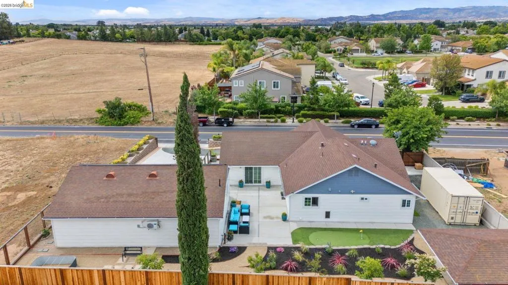Expansive rear exterior featuring a putting green, concrete patio, and fenced perimeter