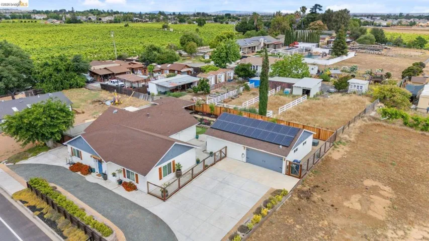 Property featuring a spacious main residence, a detached garage with solar panels, a paved driveway, and ample undeveloped land