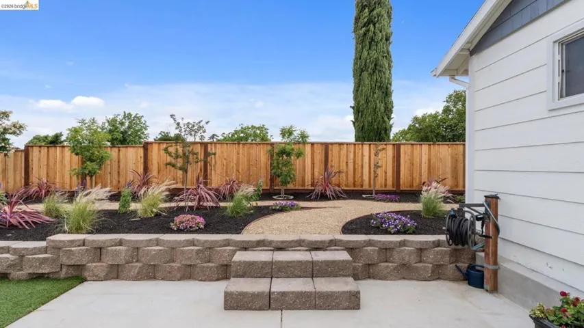 Tiered backyard landscaping featuring a block retaining wall with integrated steps