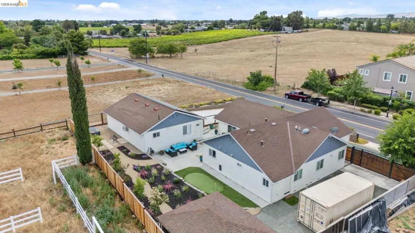 Aerial view showcasing multiple structures, a putting green, and a landscaped patio area