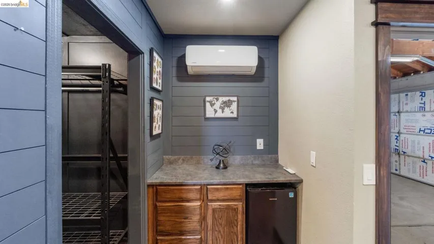 Built-in cabinetry with a dark countertop, integrated compact refrigerator, and wall-mounted climate control unit