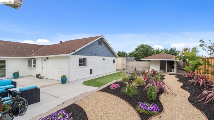 Expansive backyard featuring a gravel pathway, established plantings, and a dedicated putting green