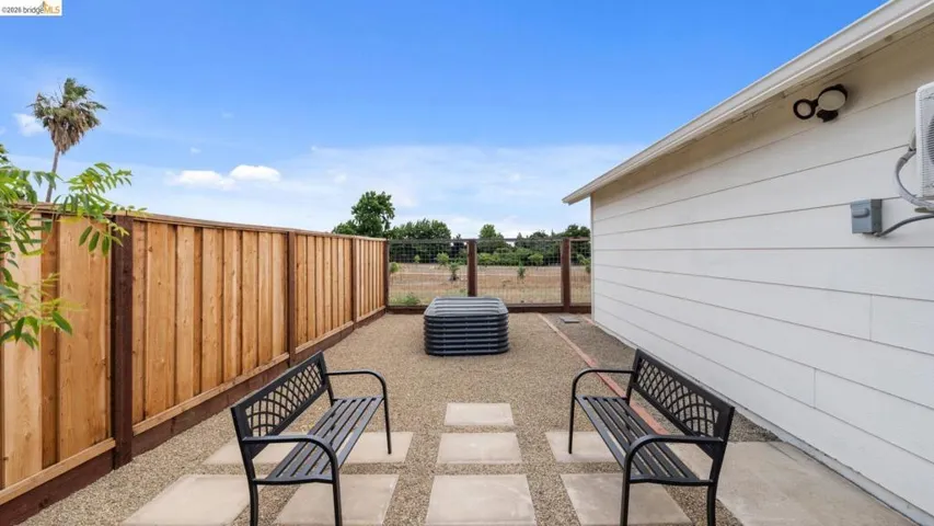 Gravel patio space featuring concrete stepping stones and a wooden privacy fence