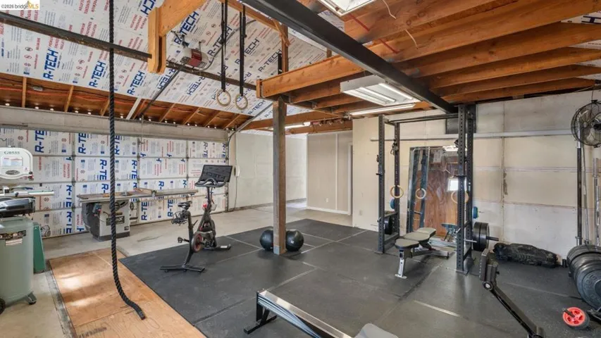 Spacious multi-purpose room featuring exposed wood beams, skylights, and a comprehensive rubber mat flooring system