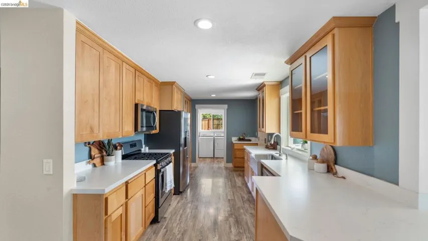 Galley kitchen featuring light wood cabinetry, light countertops, wood-finish flooring, and recessed lighting