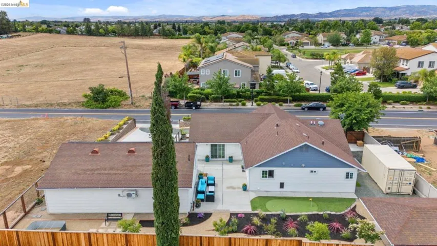 Expansive rear exterior featuring a putting green, concrete patio, and fenced perimeter