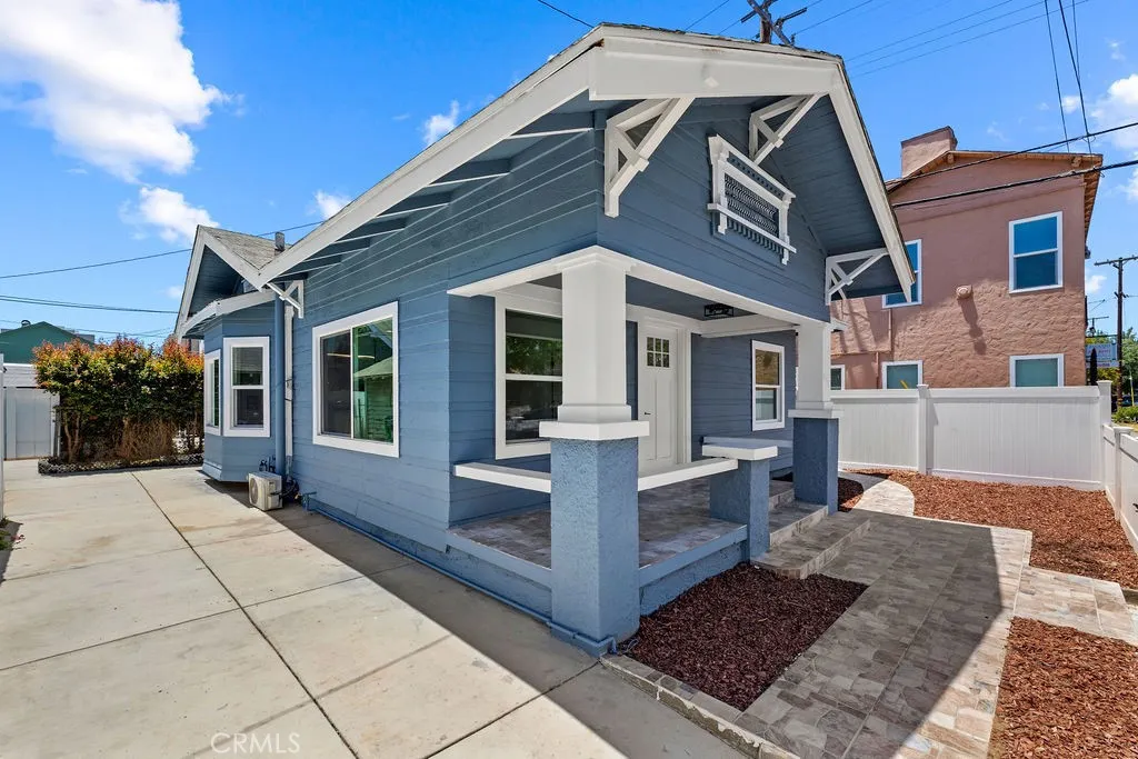 Angled front exterior view highlighting the covered front porch, resurfaced patio space, and oversized gated driveway.