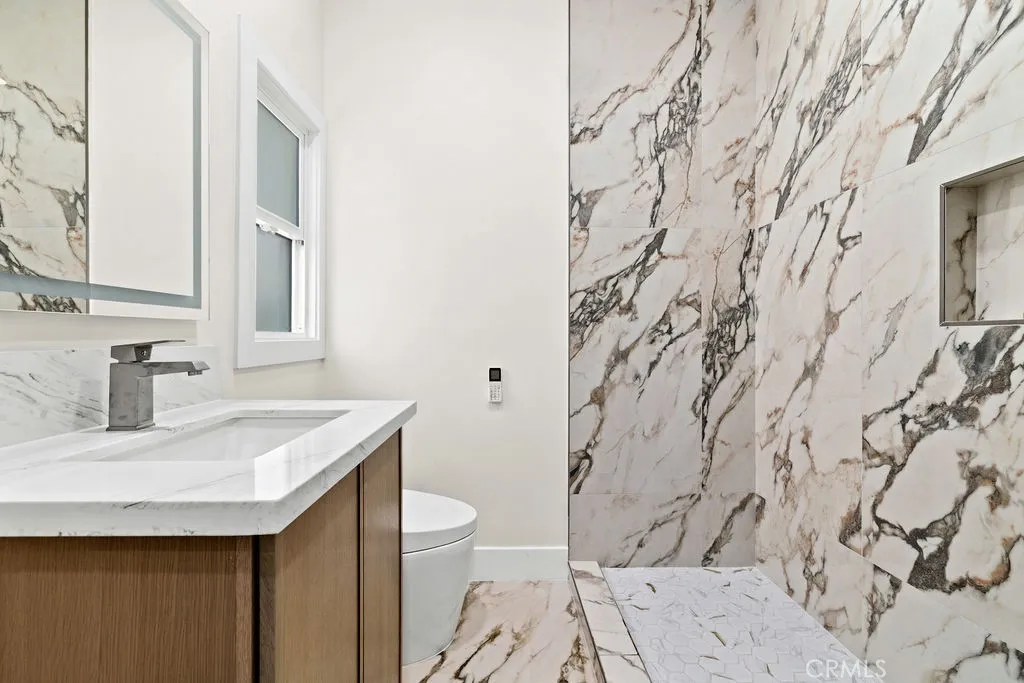 Luxuriously remodeled bathroom with dramatic Italian marble tile surround and updated fixtures.