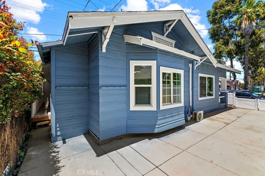 Side exterior view highlighting the oversized concrete driveway and updated exterior finishes.