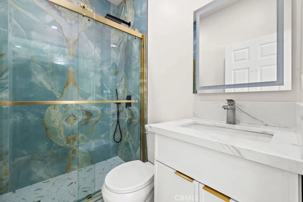 Designer bathroom featuring floor-to-ceiling Italian marble tile, modern vanity, and gold accents.
