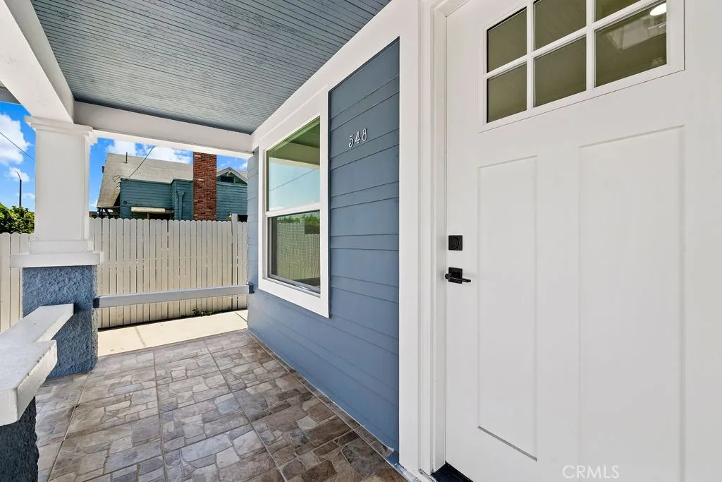 Covered front entry with tiled flooring and updated front door detail.