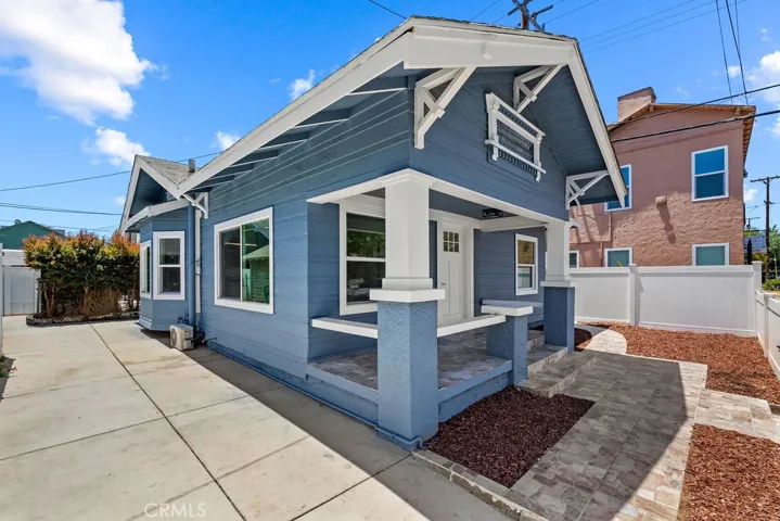 Angled front exterior view highlighting the covered front porch, resurfaced patio space, and oversized gated driveway.