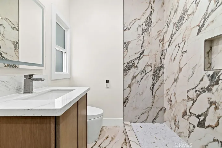 Luxuriously remodeled bathroom with dramatic Italian marble tile surround and updated fixtures.
