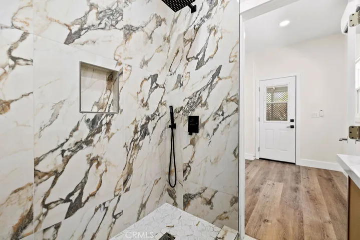 Walk-in shower detail featuring striking floor-to-ceiling marble tile and matte black fixtures.