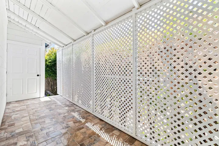 Covered rear patio that leads to laundry room with tiled flooring and privacy lattice enclosure for additional outdoor flexibility.