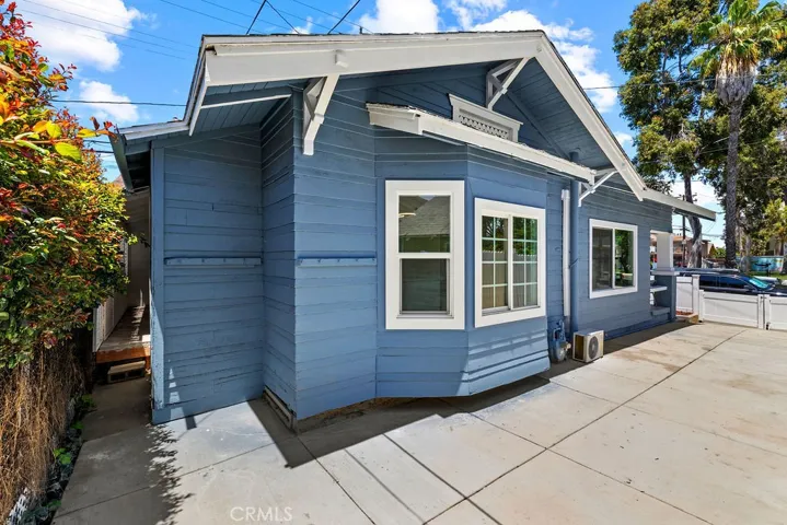 Side exterior view highlighting the oversized concrete driveway and updated exterior finishes.