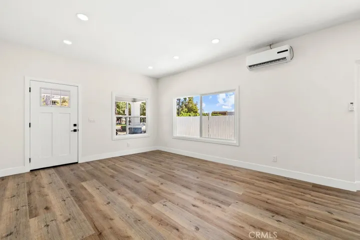 Open living room with mini-split heating and air conditioning system and updated vinyl windows.
