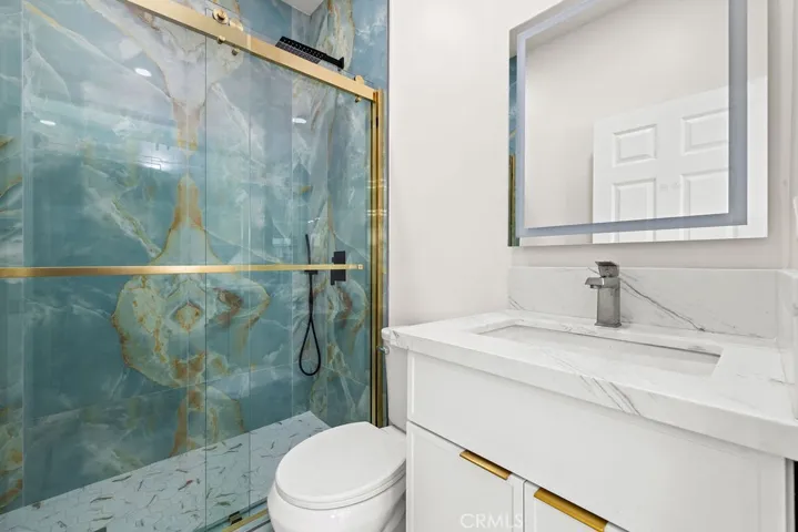 Designer bathroom featuring floor-to-ceiling Italian marble tile, modern vanity, and gold accents.