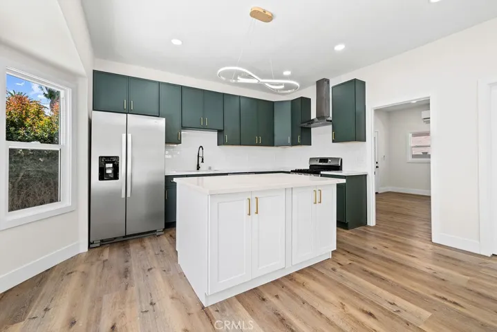 Fully renovated open-concept kitchen featuring quartz countertops, large center island, and stainless steel appliances.