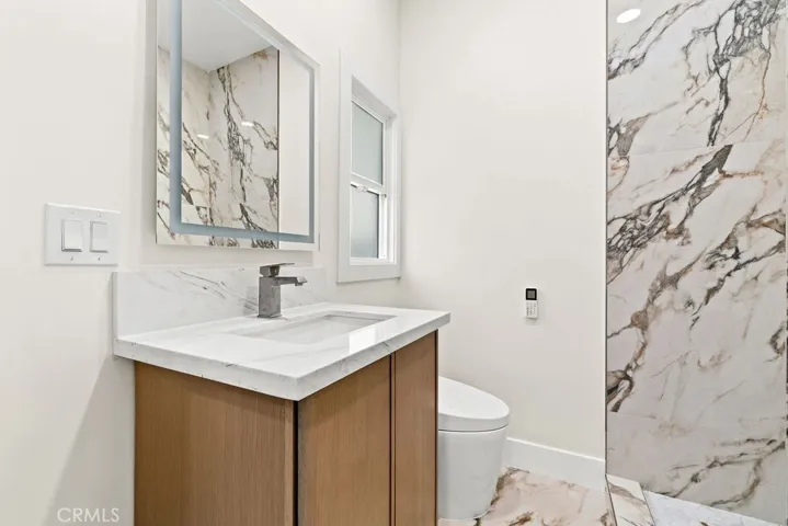 Secondary bathroom showcasing modern vanity, marble-style tile work, and contemporary finishes.