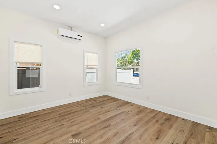 Secondary bedroom offering updated flooring, recessed lighting, and multiple windows for natural light.