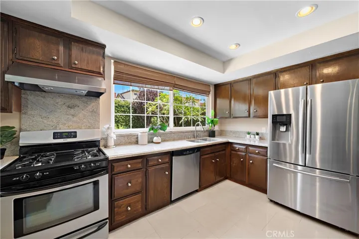 The spacious open-concept design is beautifully upgraded throughout with French-style dual pane windows and sliders, recessed lighting, marble-style tile flooring across the lower level, wide-plank wood laminate flooring upstairs, central A/C, and remodeled kitchen and baths.
