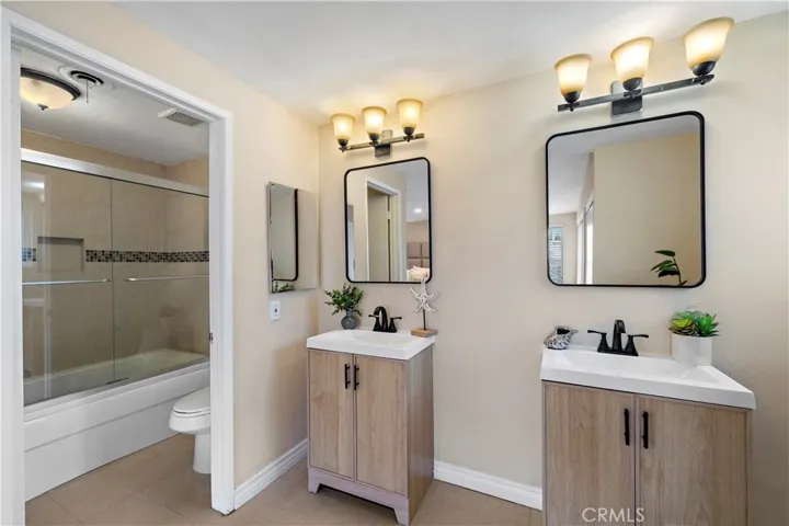 a spacious retreat area, and an ensuite bath with dual vanities. All three bathrooms have been stylishly upgraded with quartz countertops, white shaker cabinetry, newer fixtures, and tub/shower combinations with designer tile surrounds and clear glass enclosures