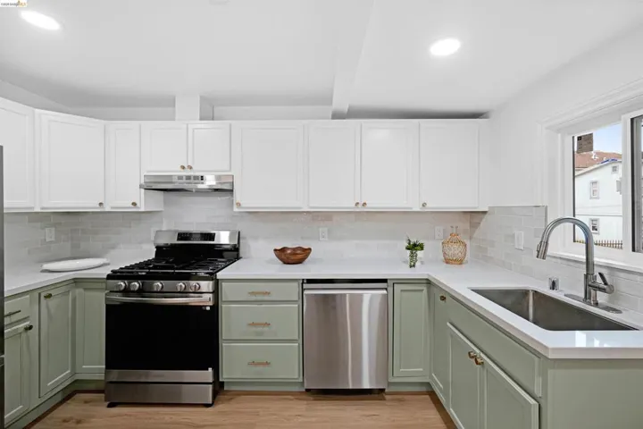 Modern kitchen featuring two-tone cabinetry with white upper and light green lower cabinets, stainless steel appliances, white countertops, and a subway tile backsplash