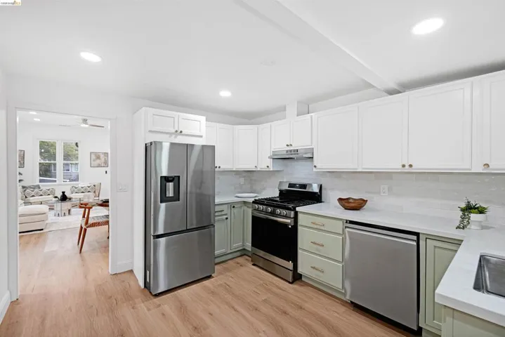 Modern kitchen featuring wood-finish flooring, white upper cabinetry, and light green lower cabinetry