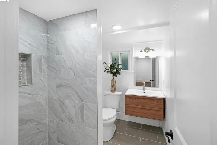 Contemporary bathroom showcasing a floating wood-finish vanity with a rectangular sink, brushed nickel faucet, and coordinating wall-mounted light fixture