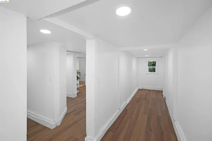 Hallway featuring wood-finish flooring, recessed lighting, white walls, and a window with exterior visibility