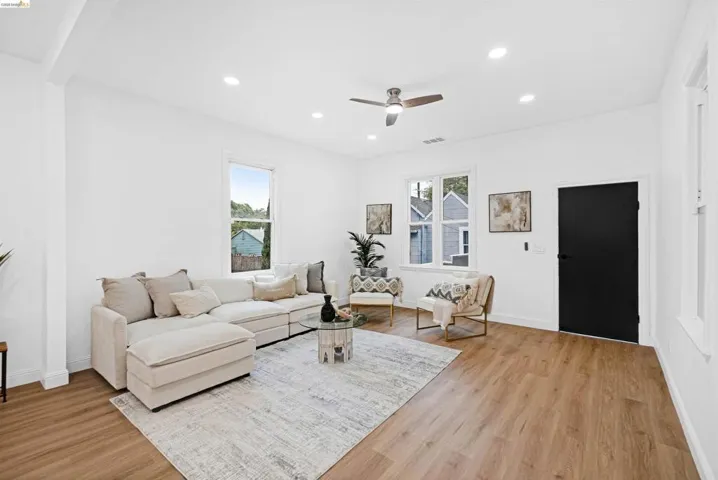 Spacious living area featuring light wood-finish flooring, recessed lighting, and a ceiling fan