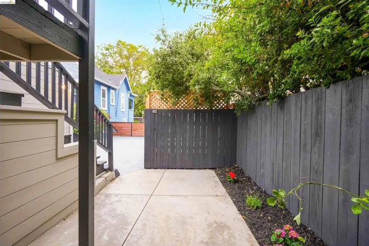 Concrete walkway with a dark wood privacy fence, leading to a wooden gate