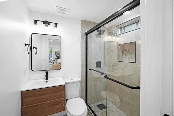 Modern bathroom featuring a glass-enclosed shower with tiled walls and a hex-tile floor