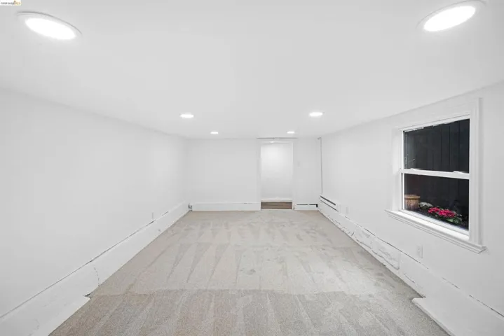 Carpeted room featuring recessed lighting, a single window, and a baseboard heating unit