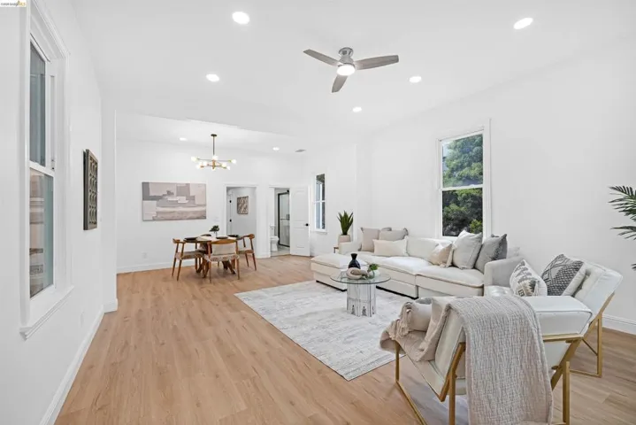 Open-concept living and dining area featuring wood-finish flooring, recessed lighting, and white walls