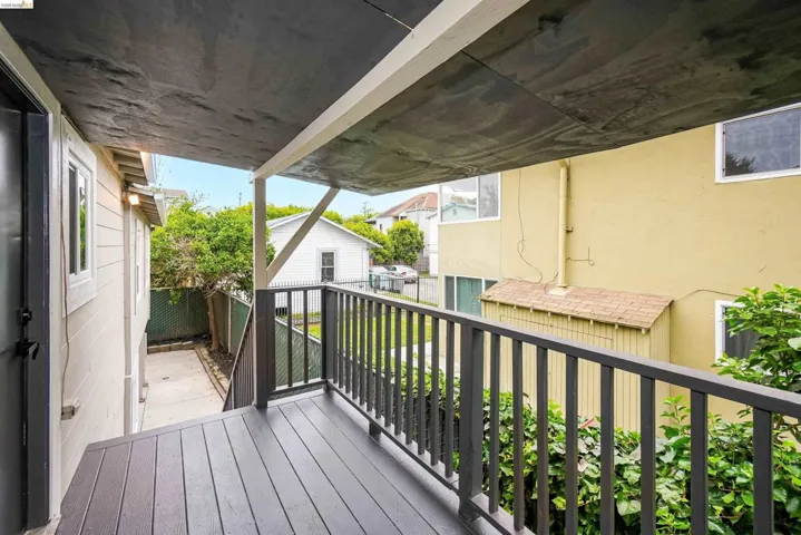 Exterior balcony featuring composite decking, dark gray railings, and a solid overhead covering