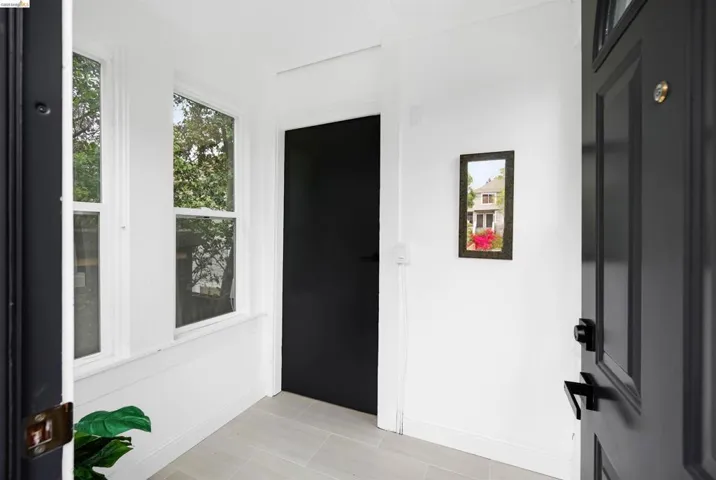 Entryway featuring a paneled door with matte black hardware, light-toned tile flooring, and multiple windows