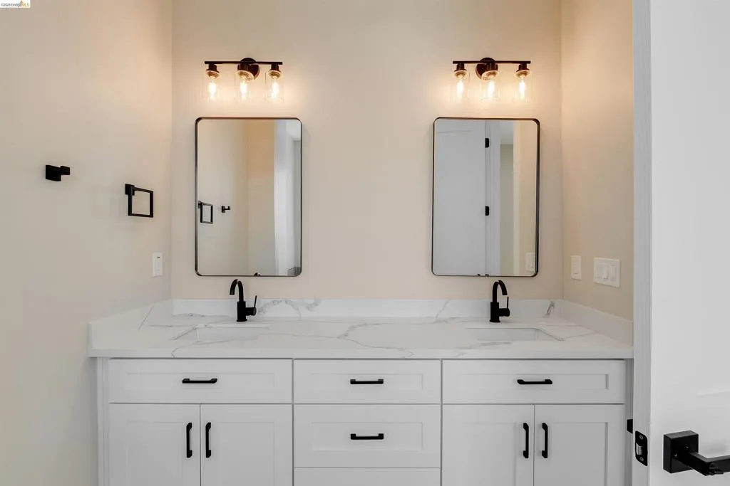 Double vanity with white cabinetry, matte black hardware, and integrated sinks