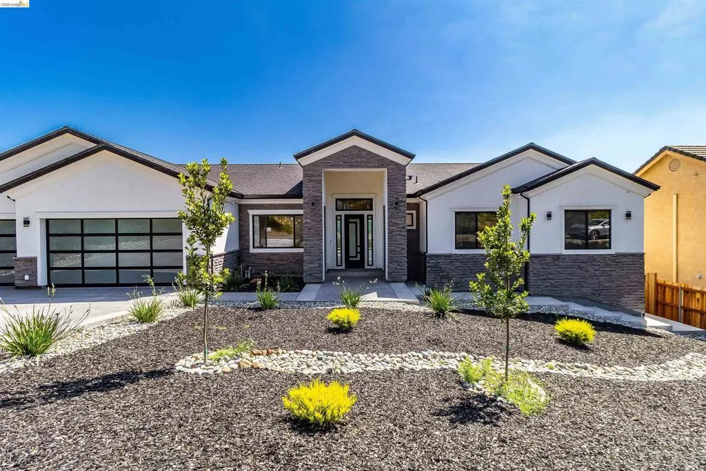 Contemporary ranch-style exterior featuring a striking stone facade, stucco accents, and a covered entry