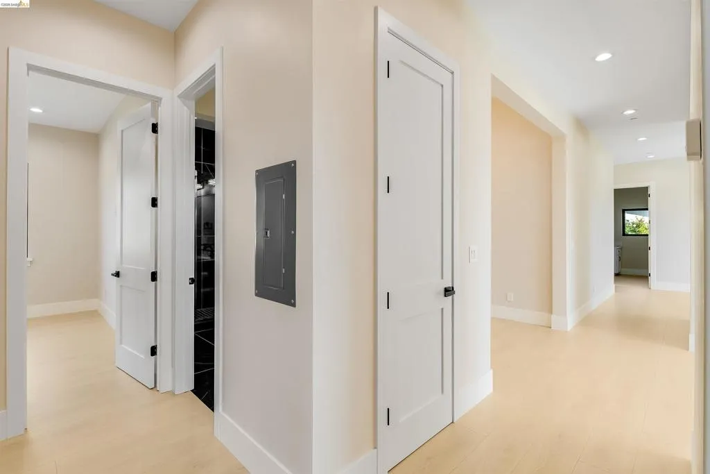Bright hallway with light wood-finish flooring, recessed lighting, and white baseboards