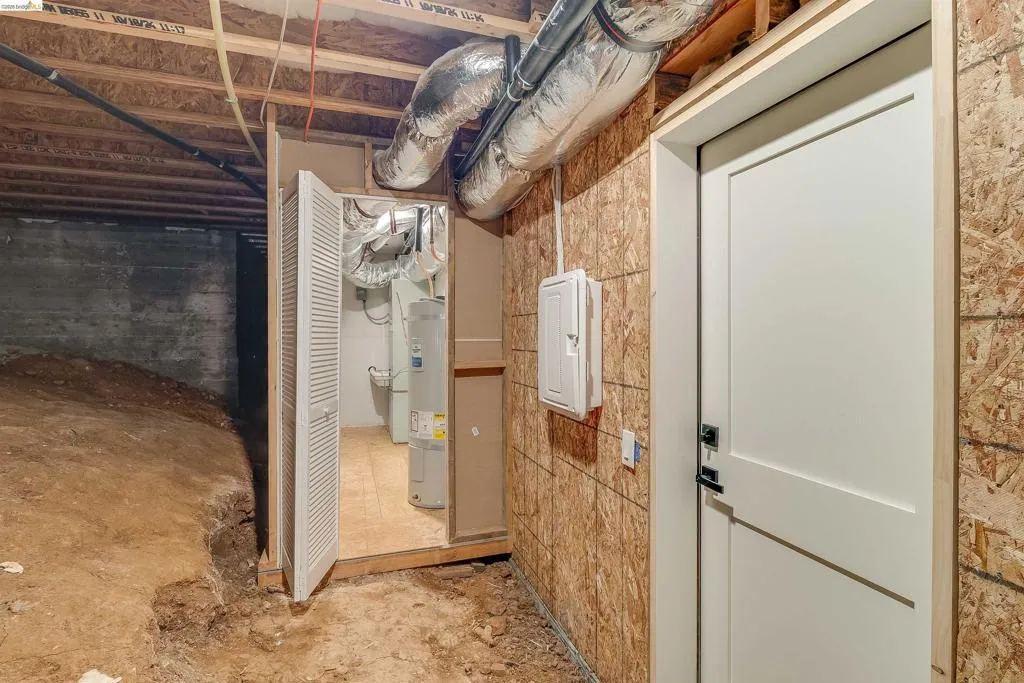 Exposed ceiling joists and ductwork with a white panel door and electrical panel